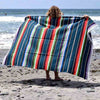 Person holding a colorful striped towel on a beach