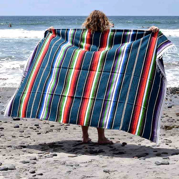 Person holding a colorful striped towel on a beach