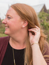 Close-up of boomerang-shaped brass stud earrings by Fair Anita on white background