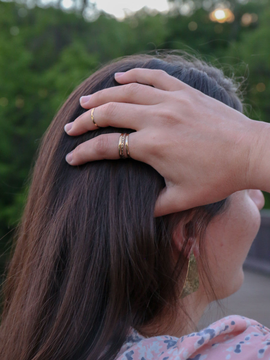 Close-up of dainty fair trade brass stacking rings showing varied surface textures