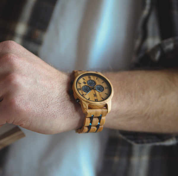 Wooden wristwatch on a person's wrist with a blurred background