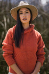 Woman wearing a red sweater and beige hat outdoors