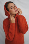 Woman wearing a red knitted sweater against a plain background