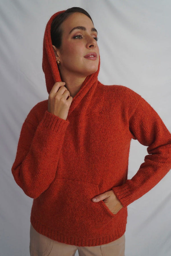 Woman wearing a red knitted sweater against a plain background