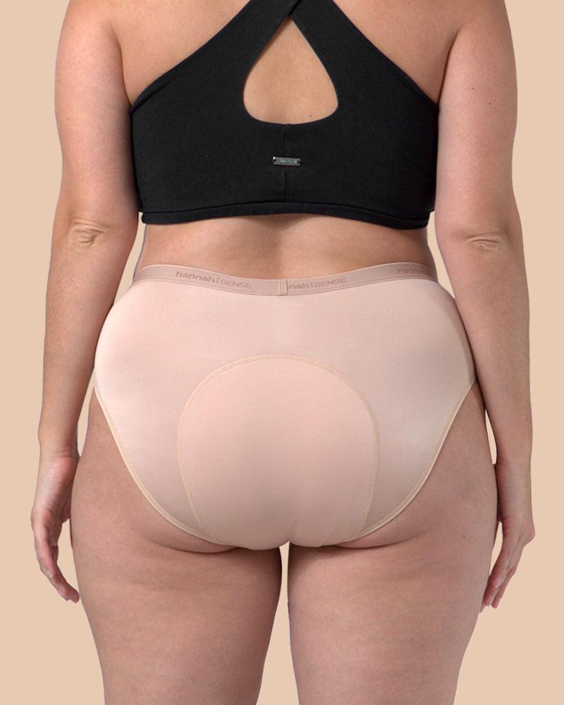 Person wearing a black sports bra and beige underwear on a beige background