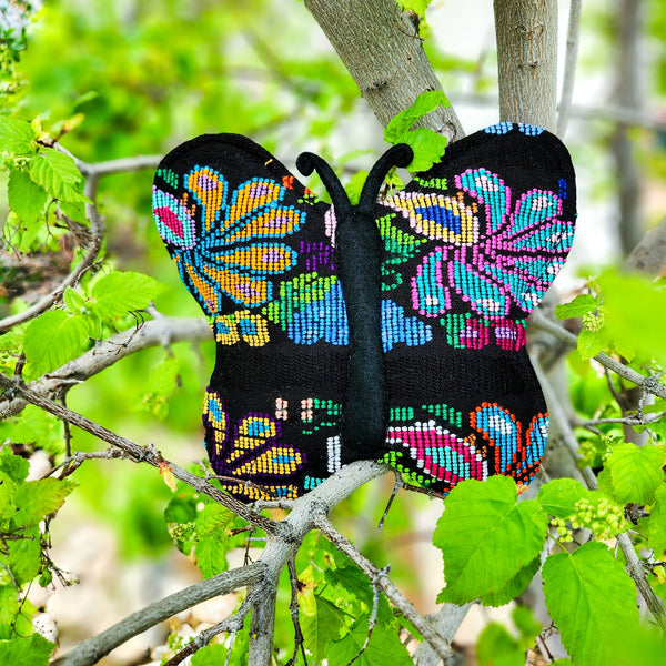 Colorful butterfly-shaped object on a branch with green leaves