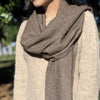 Person wearing a brown scarf with a blurred natural background