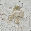 Gold sunburst ring and earrings on a textured stone surface