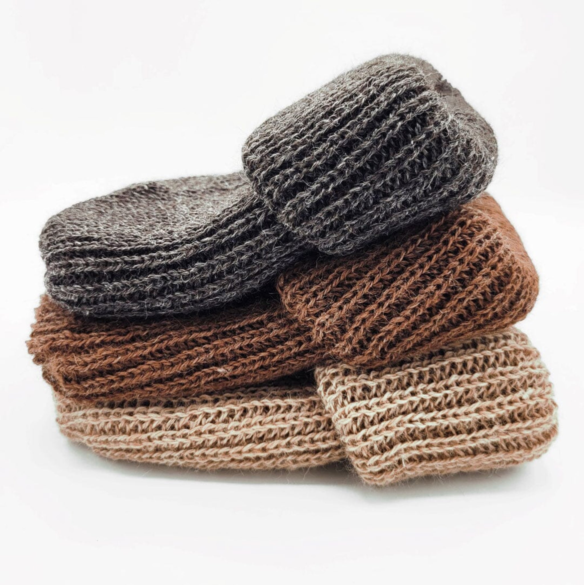 Stack of brown and gray knitted slippers on a white background