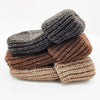 Stack of brown and gray knitted slippers on a white background