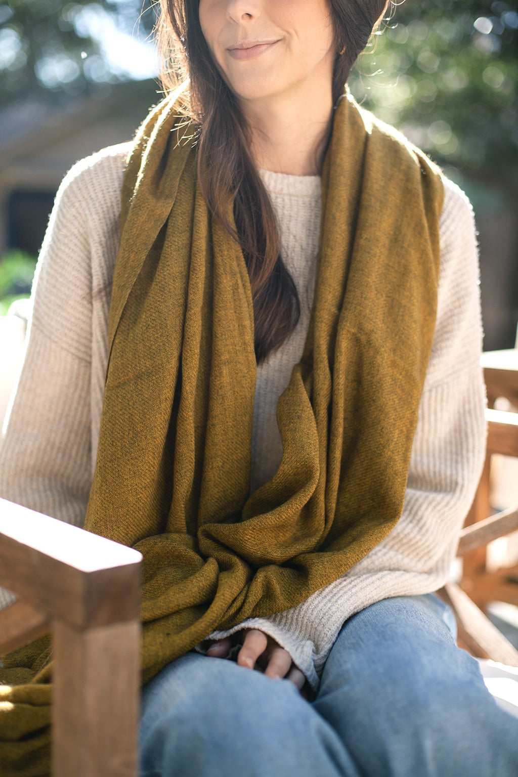 Woman wearing a mustard yellow cashmere scarf sitting outdoors