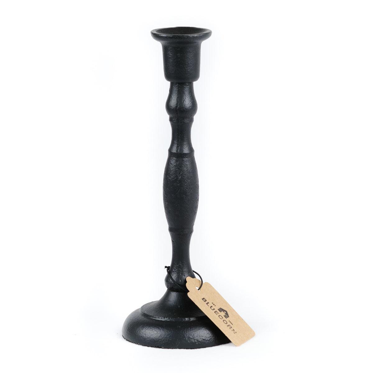 Two cast iron taper candle holders by Bluecorn Candles in small and large sizes on a neutral background