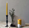 Close-up of a single cast iron taper holder with a hand-dipped beeswax taper candle
