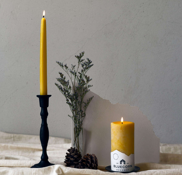Close-up of a single cast iron taper holder with a hand-dipped beeswax taper candle