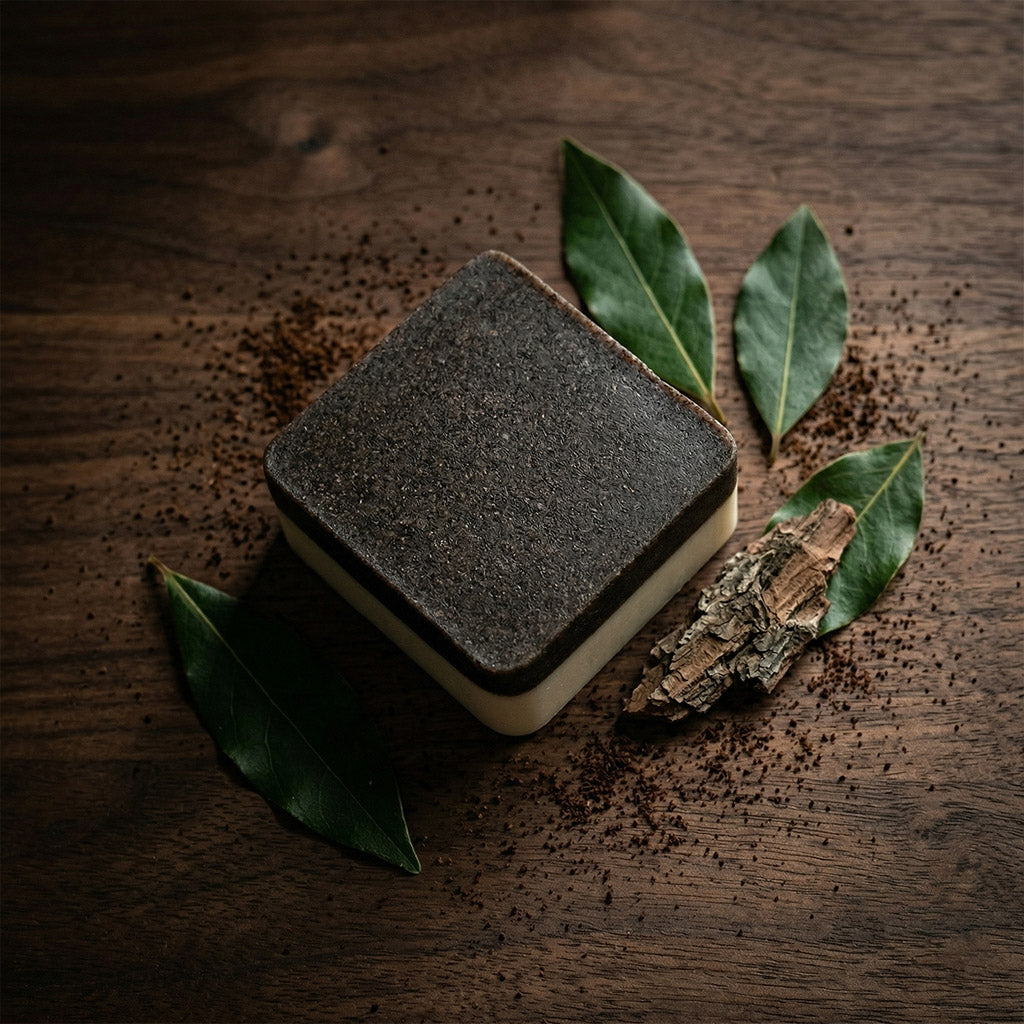 Square black and white soap with green leaves on a wooden surface