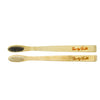 Two bamboo toothbrushes with black and white bristles on a white background, branded 'Lucky Teeth'.