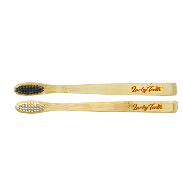 Two bamboo toothbrushes with black and white bristles on a white background, branded 'Lucky Teeth'.