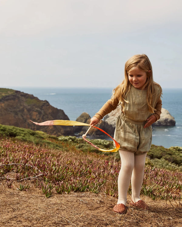Young girl playing with a ribbon on a coastal cliffside