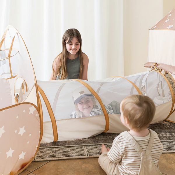 Children playing inside a star-patterned play tent in a home setting.