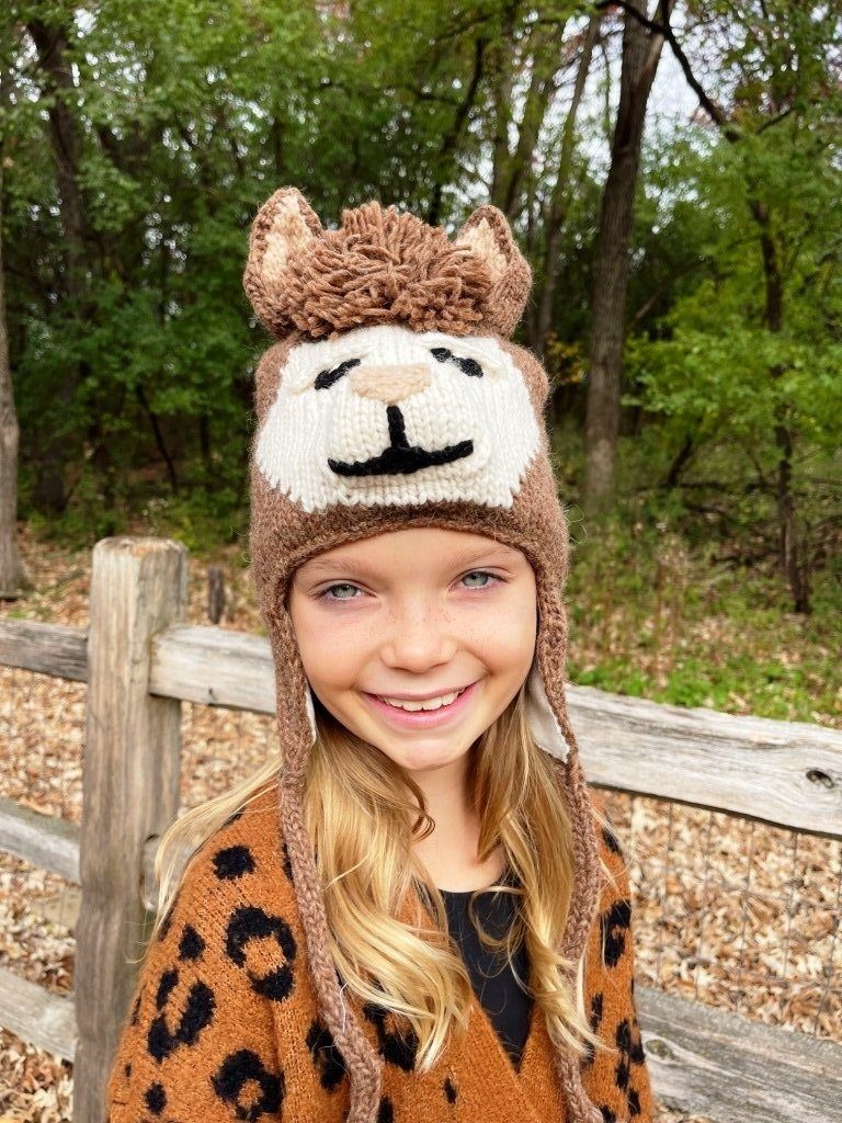 Child wearing a lion-themed knitted hat in a forest setting