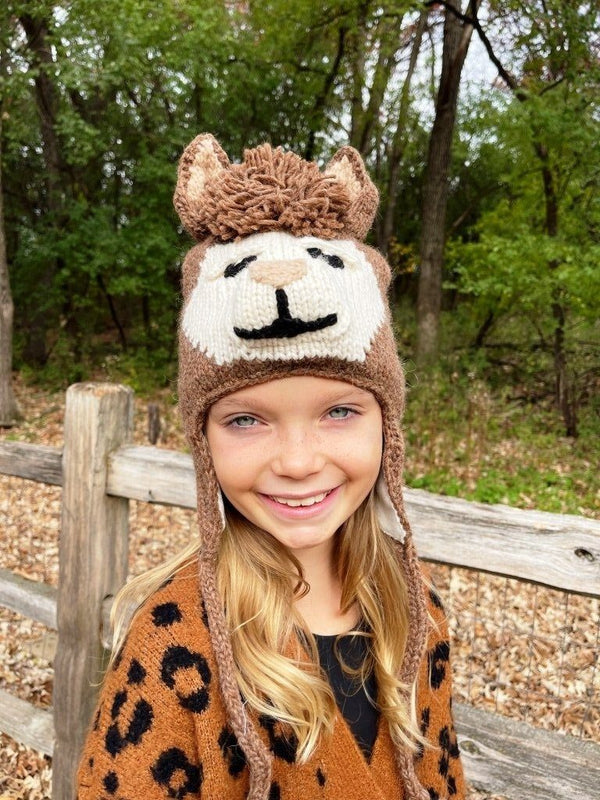 Child wearing a lion-themed knitted hat in a forest setting