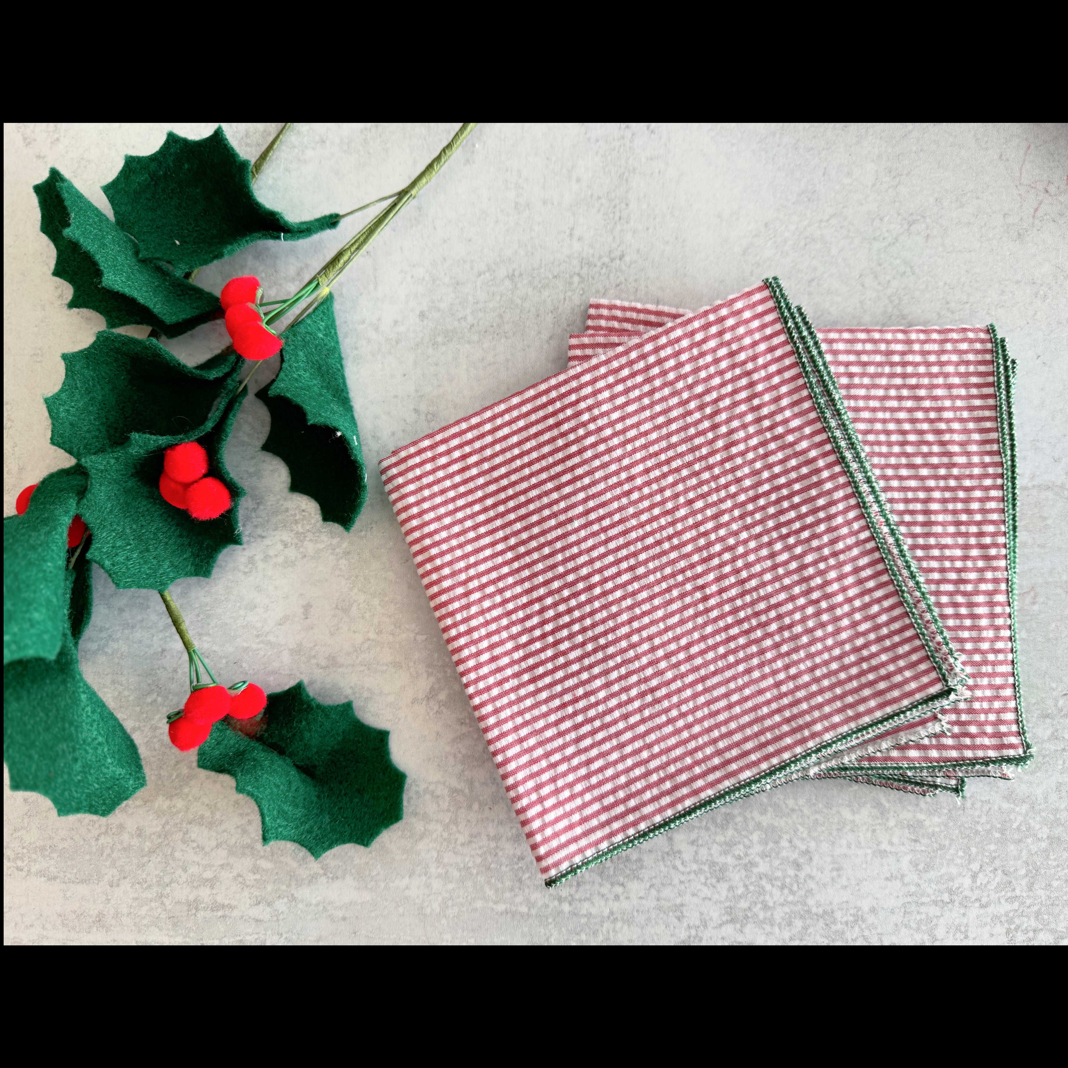 Red seersucker cocktail napkins with forest green edging, set of four, styled for a holiday table