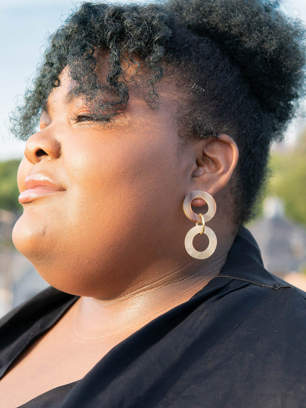Close-up of circular triple loop horn earrings with natural earthy tones by Fair Anita