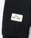 Black knit sweater with a label on a white background. Classic Alpaca Socks – soft, breathable, and versatile for year-round wear. Ethically made in Peru. Shop timeless alpaca comfort today.