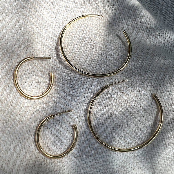 Gold hoop earrings on a textured white surface
