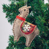 Felt llama ornament with red saddle and white snowflake on a Christmas tree.