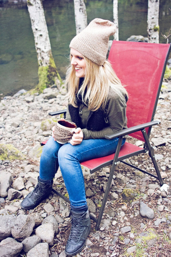 Woman sitting on a red camping chair by a body of water