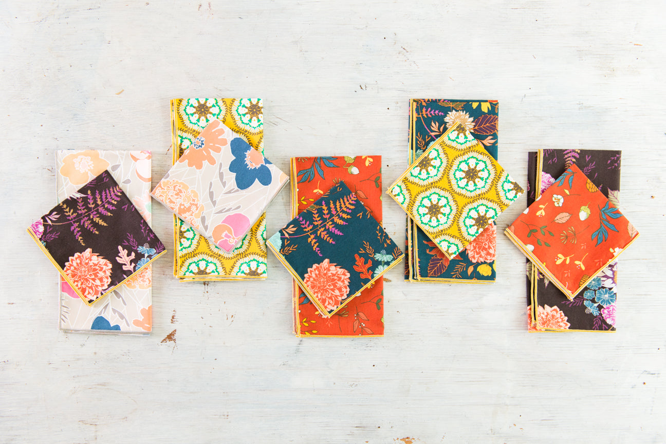 Blue floral cloth napkins and cocktail napkins folded on a wooden board