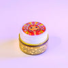 Lip gloss container with colorful label on a light purple background