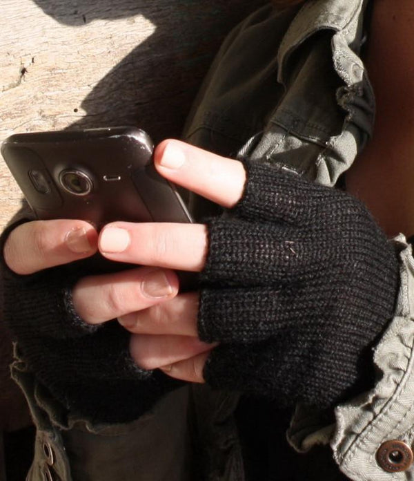 Person wearing black fingerless gloves using a smartphone.