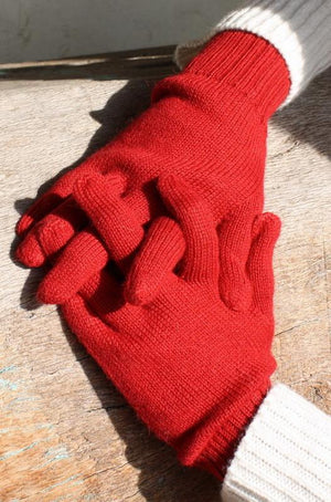 Red 100% alpaca full finger knit gloves on a wooden surface
