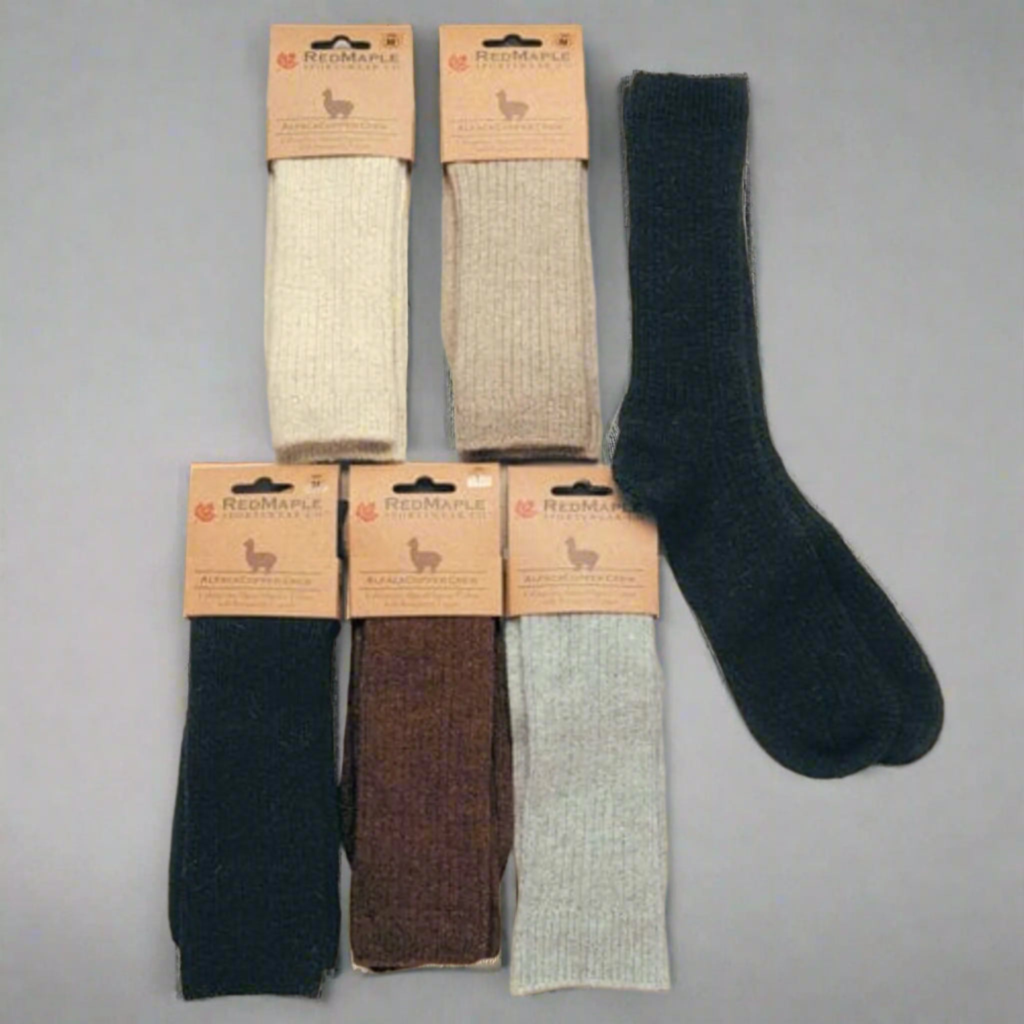 Set of six pairs of socks with packaging on a beige background. Experience the benefits of our Copper Crew Alpaca Socks. Made with undyed alpaca and organic cotton, these socks feature heat-reflecting copper fibers. Machine washable and incredibly soft for daily comfort.