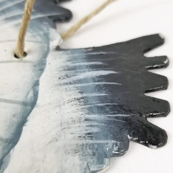 Decorative metal fish ornament with a textured surface on a white background