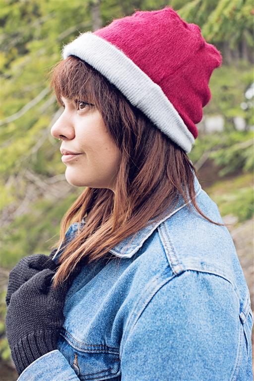 Person wearing a red and gray beanie outdoors with greenery in the background