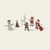 Set of Christmas-themed figurines including a snowman, reindeer, and elves on a beige background