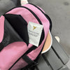 Pink baby carrier with a white packet labeled 'Freedom' on a gray surface.
