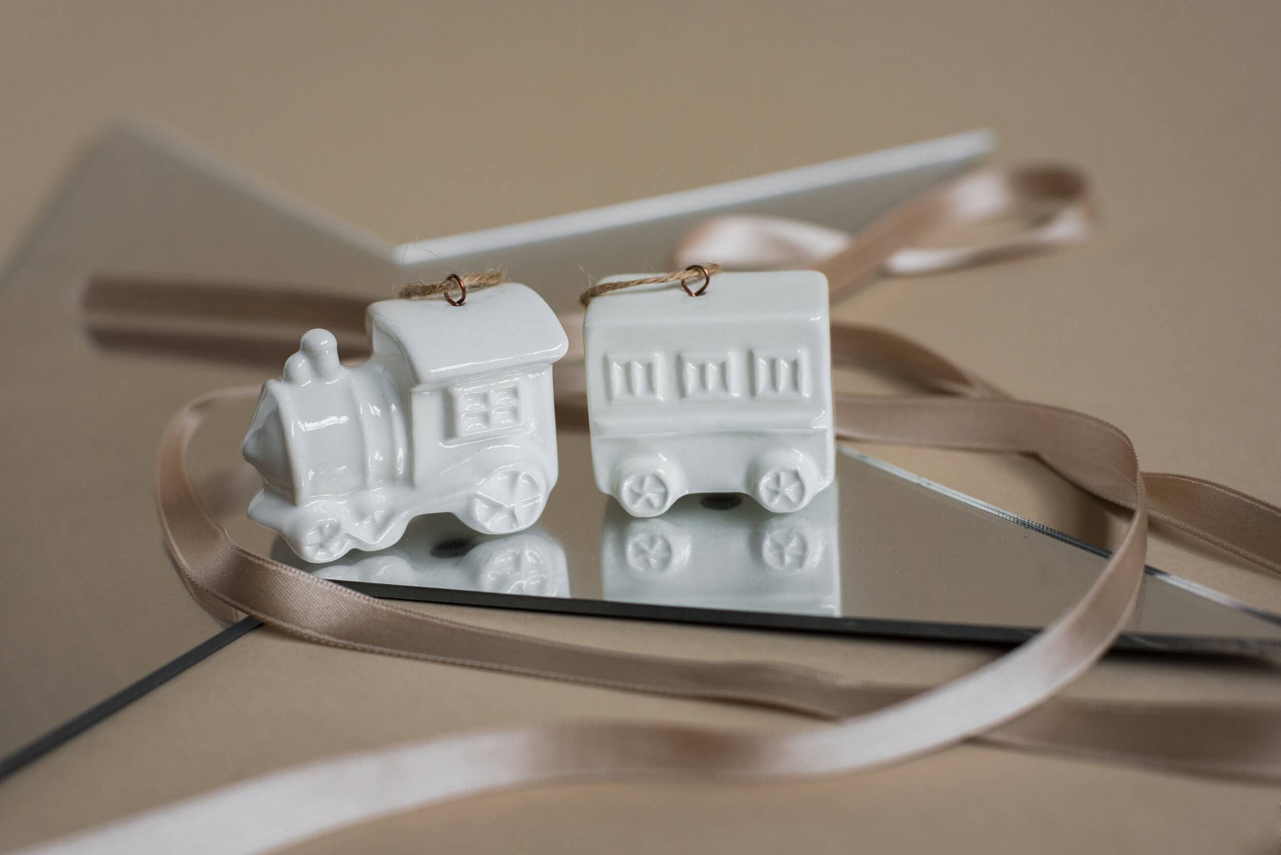 White ceramic train set on a reflective surface with a beige background