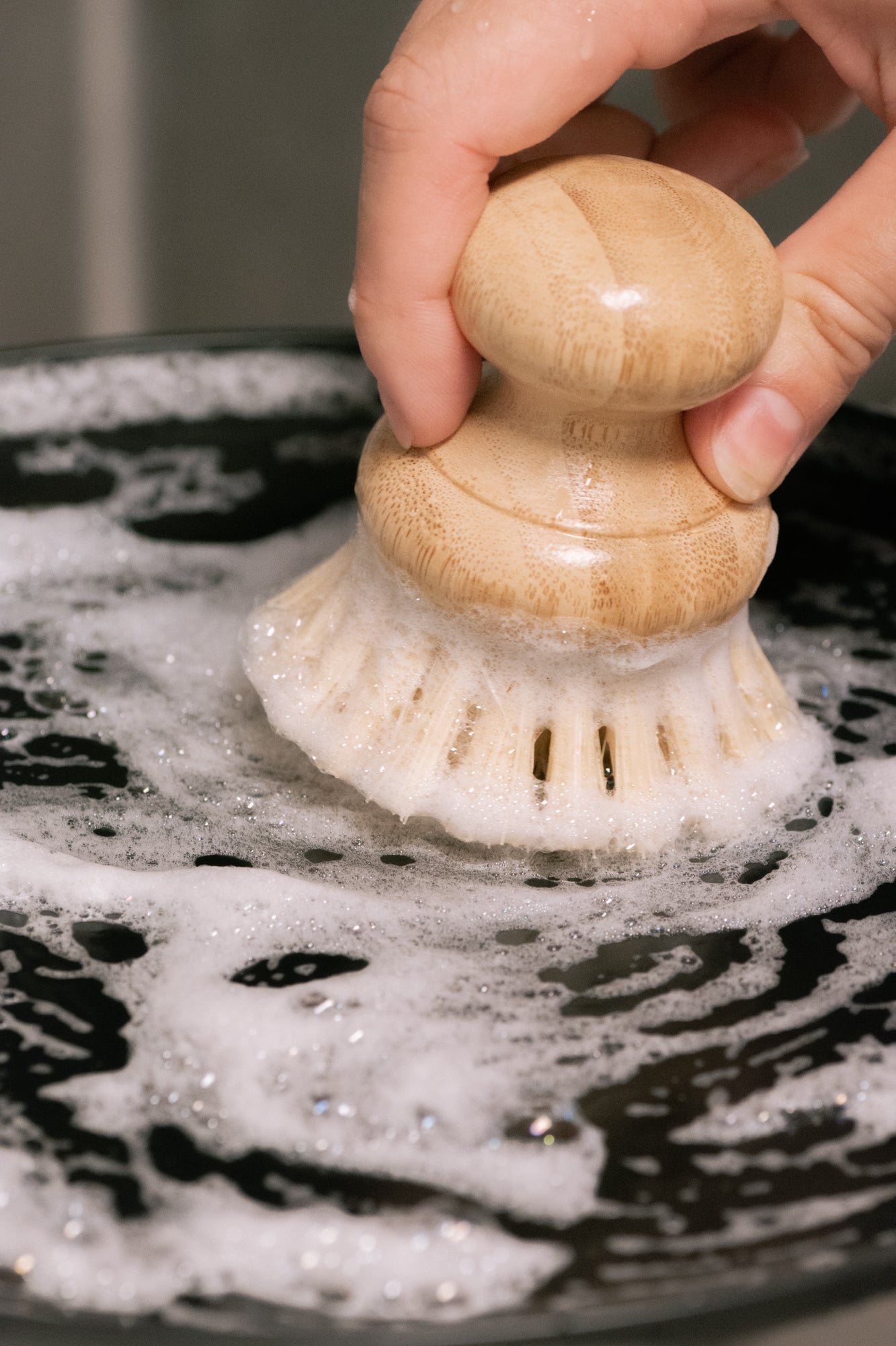 Hand using a scrubber on a soapy surface