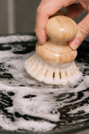 Hand using a scrubber on a soapy surface