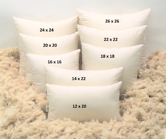 Set of white pillows with measurements on a textured surface