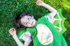 Child in a green dinosaur costume lying on grass