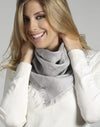 Woman wearing a gray scarf and white sweater against a neutral background