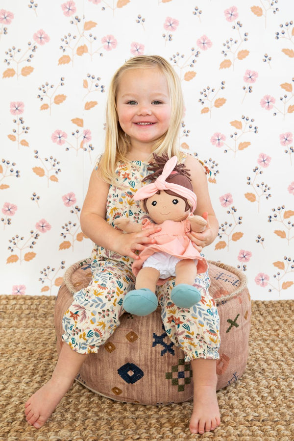 Flatlay of Earthtone Floral Tie Shoulder Jumpsuit with Paloma doll and coordinating organic muslin doll clothes accessories