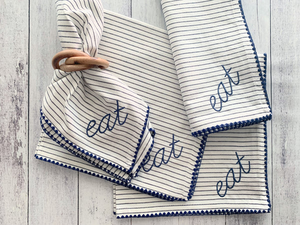 Wood bangle napkin ring styled with striped embroidered dinner napkins on a table setting