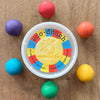 Container of eco-dough with colorful balls on a wooden surface
