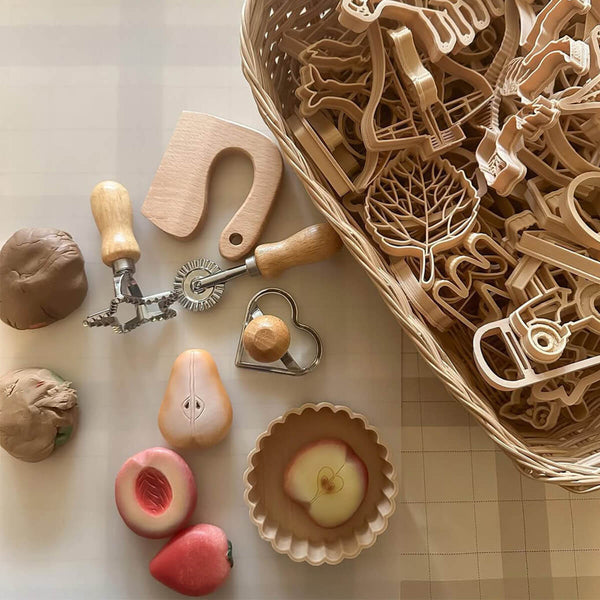 Wooden cookie cutters and shaped dough on a light surface